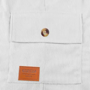 Détail du short en velours côtelé blanc avec poche à rabat et écusson en cuir classique