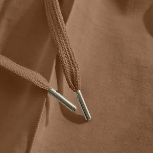 Close-up of drawstring with metal aglets on brown casual cotton pants fabric