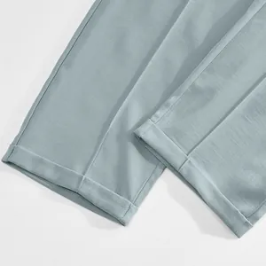 Detail showing neat cuffed hems of light blue minimalist men's casual trousers.