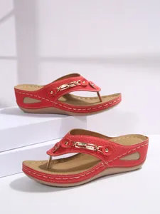 Detail of red wedge flip-flop sandals with metal chain and rhinestone decorations