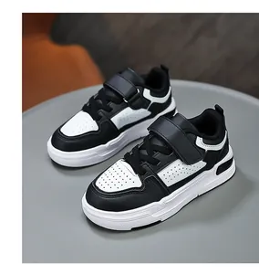 Detail view of kids' black and white sneakers with velcro straps and leather panels.