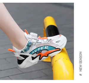 Close-up of kids' mesh running shoe with orange accents and rotary buckle lacing.