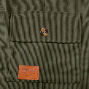 Gros plan du tissu en velours côtelé vert olive avec poche et écusson en cuir