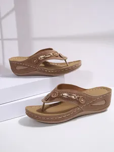 Detail of women's brown wedge thong sandals featuring elegant metal chain and rhinestones.