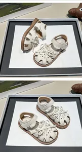Detailed view of white girls' closed-toe sandals with bow and cutout patterns