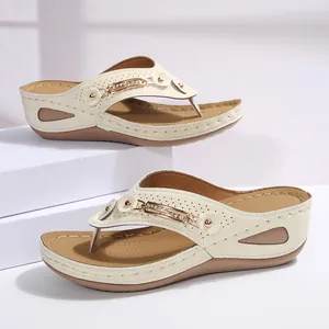Elegantes sandalias de cuña color crema con cadena metálica para la playa en verano.