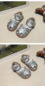 Detailed view of silver girls' sandals with delicate bow and star cutouts