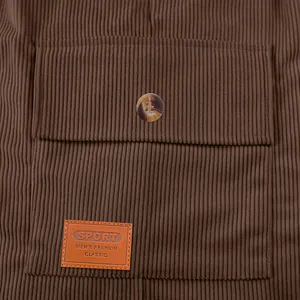Detailreiche Makroansicht der braunen Cord-Cargotasche mit Knopf und geprägtem Lederpatch