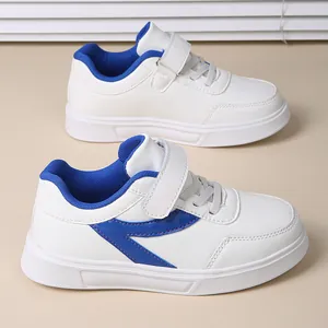 Detail view of white girls sneakers featuring blue accents and convenient velcro straps.