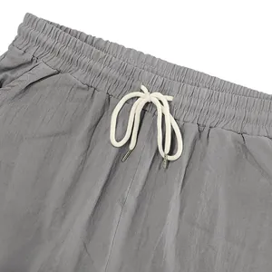 Primo piano dell'elastico in vita e della coulisse bianca sui pantaloncini di lino grigi
