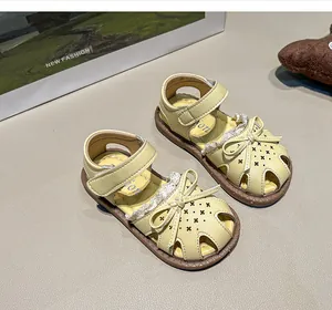 Detailed view of yellow toddler girl sandals with bow and lace in a lifestyle setting