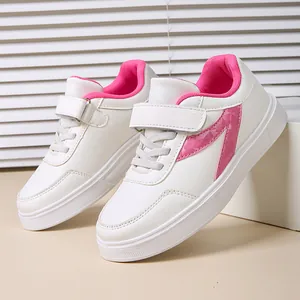 Close-up detailed view of girls' white and pink sneakers featuring a velcro strap design