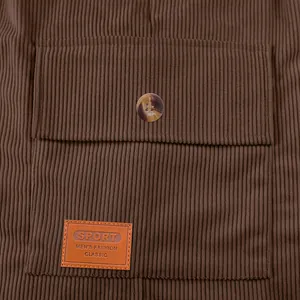 Détail d'une poche en velours côtelé marron avec écusson en cuir et bouton décoratif