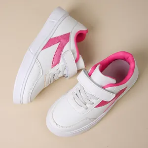 Detailed view of girls white board sneakers with vibrant pink accents and Velcro straps