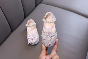 Close-up of sparkling rhinestone girls' princess shoes with pearl strap for parties