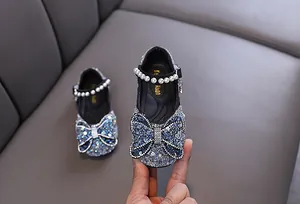 Close-up of sparkly blue girl's princess shoe with sequined bow and pearl strap