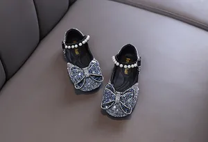 Close-up of girls' blue glitter Mary Janes with rhinestone bow and pearl strap