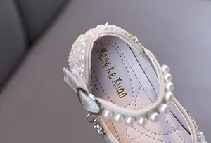 Macro detail of toddler girl's white princess shoe with pearls and sparkling rhinestones