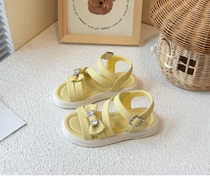 Detailed view of yellow girl's princess sandals featuring a rhinestone bow accent