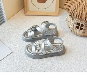 Close-up detail of silver girl's princess sandals with rhinestone bow decoration
