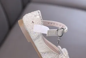 Macro view of glittering rhinestones and pearl details on ivory girls princess shoes