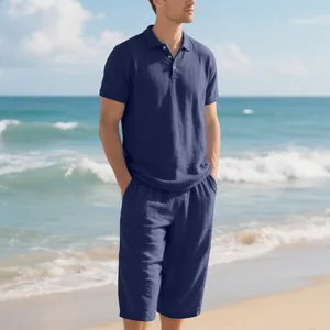 Detailed view of men's navy blue linen polo shirt and cropped pants on a beach