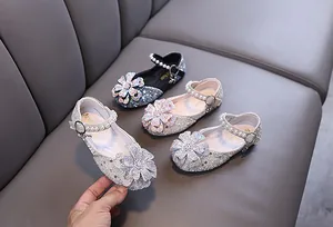 Detailed view of sparkly girls' Mary Jane shoes featuring rhinestone flower and pearl strap.