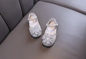 Detailed view of rhinestone flower and pearl strap on girls princess shoes.