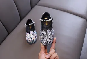 Close-up detail of girls' silver princess shoes with large rhinestone flower and pearls