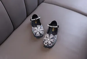 Close-up of sparkling rhinestone flower and pearl strap on girl's princess shoes