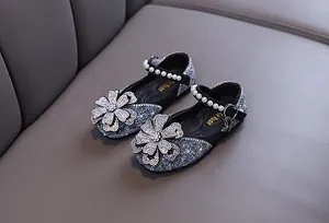 Macro view of girl's silver glitter Mary Jane shoes with rhinestone flower ornament