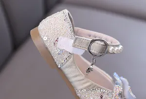 Detailed close-up of girl's princess shoe featuring iridescent sequins and pearl strap buckle