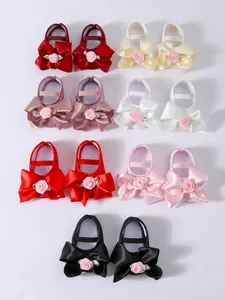 Variedad de zapatos de bebé estilo princesa con lazos grandes de satén y rosas rosas.