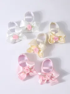 Primer plano de zapatos de princesa para bebé con suela blanda y lazos elegantes.