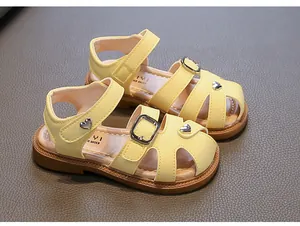 Close-up of yellow girls' sandals with heart accents and soft brown soles