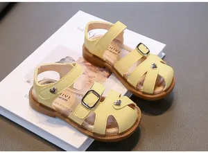 Detailed top view of yellow girls' closed-toe sandals with heart charms