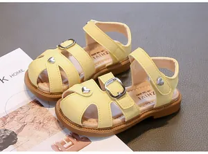 Detailed view of trendy yellow closed-toe girls' summer sandals with cute heart charms