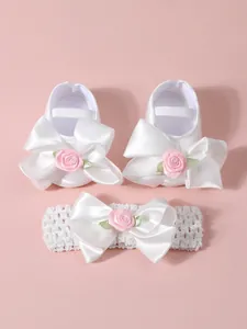 Primer plano de zapatos de princesa blancos para bebé y diadema con rosas rosas