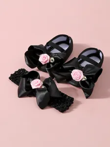Detalle de zapatos de princesa para bebé negros y diadema con lazo rosa