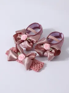 Vista detallada de zapatos de princesa de satén rosa para bebé con diadema a juego