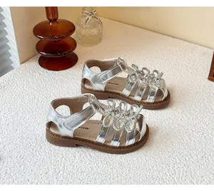 Full view of elegant silver girls' Lolita sandals with triple bow details on a white surface