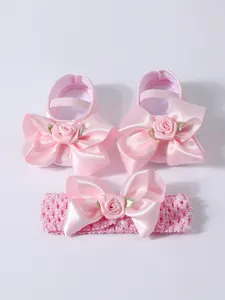 Detalle de lazos de satén rosa y rosas en zapatos de princesa y diadema para bebé