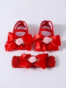 Detalle de zapatos rojos de princesa para bebé y diadema con lazo floral a juego para niños