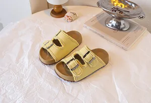 Nahaufnahme von gelben Kinder-Plateausandalen mit Metallschnallen und Fransenrand