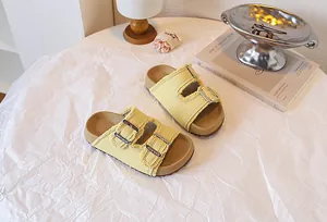 Nahaufnahme gelber Kinder-Sandalen mit doppelter Schnalle und modischen Fransenkanten.