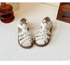 Close-up detail of off-white Lolita-style girl's sandals featuring triple bow decorations