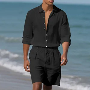 Model wearing black linen shirt and shorts set walking on a sunny beach.