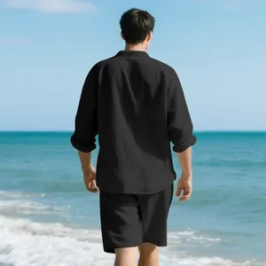 Back view of a man wearing a black linen shirt and shorts set walking on the beach