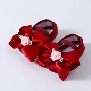 Elegantes zapatos rojos de princesa para bebé con lazos de satén y rosas.