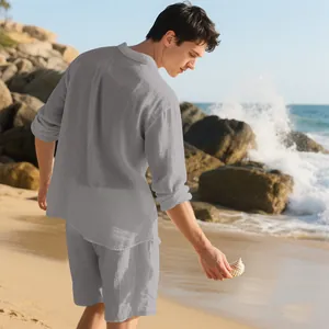 Back view of a male model wearing a grey linen shirt and shorts set on a sunny beach